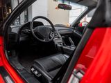 the interior of a red sports car with the door open