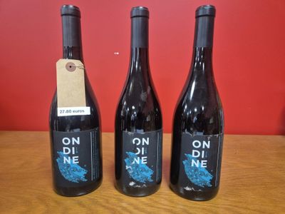 trois bouteilles de vin posées sur une table en bois
