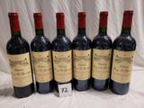 six bouteilles de vin rouge sont alignées sur une table