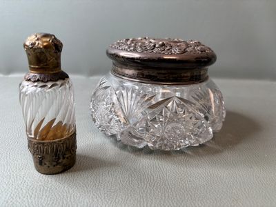 un petit bocal en verre avec un couvercle argenté, à côté d'un autre petit bocal en verre avec un couvercle argenté