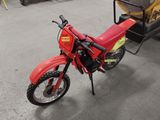 a red dirt bike parked in a garage with a trailer behind it