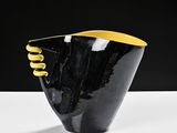 a black and yellow vase sitting on top of a white table