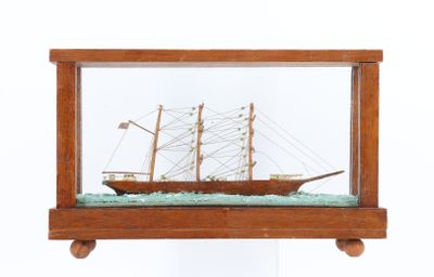 une petite maquette de bateau en bois exposée dans une vitrine