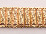 un gros plan d'un bracelet plaqué or sur une surface blanche