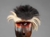 a close up of a wooden mask on a metal stand