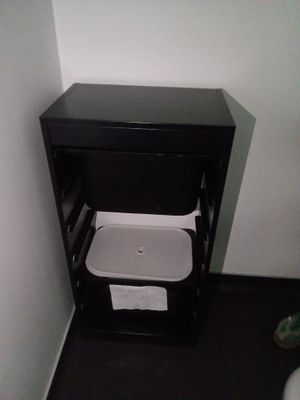 une petite armoire noire équipée de toilettes et d'un distributeur de papier essuie-mains