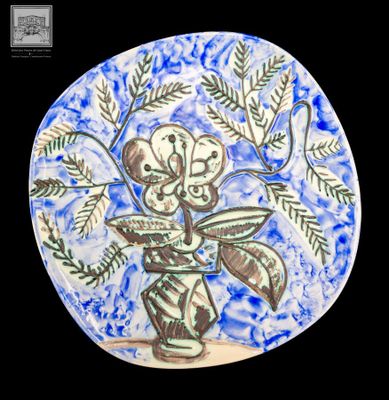 une assiette bleue et blanche sur laquelle est représenté un vase de fleurs