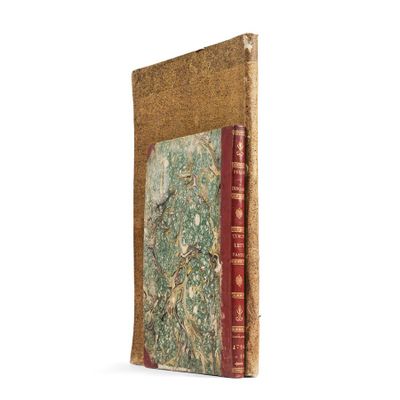 an old book with a red cover sitting on top of a white surface
