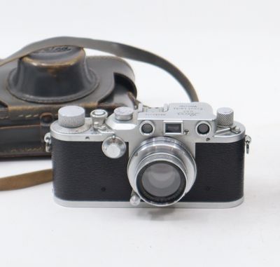 a black and white photo of a camera and a brown bag