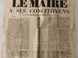 un vieux journal sur lequel est posé un stylo, posé à son tour sur une table