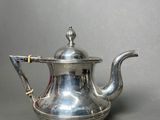 an antique silver tea pot with a handle on a grey background