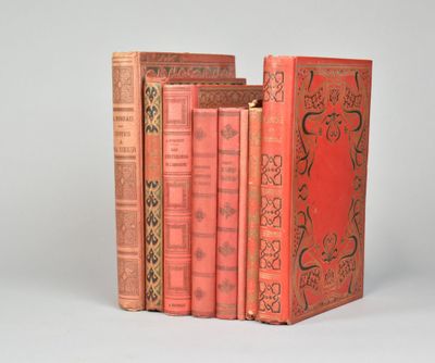 trois livres rouges superposés sur une surface blanche