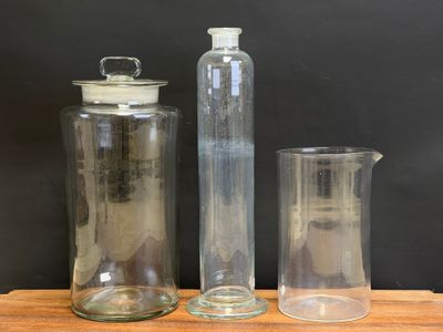 three glass containers and a glass pitcher on a wooden table