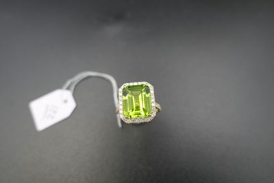 an emerald and diamond ring on a black surface