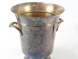 a silver vase with a handle on a white surface