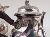 a silver tea pot sitting next to a silver tea pot