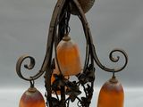 un lustre auquel sont suspendues trois lampes en verre orange