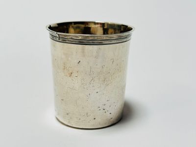 a silver cup that is sitting on a white surface