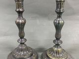 paire de bougeoirs anciens en argent sur un socle, sur fond gris