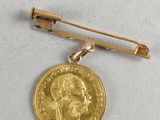 an image of a gold coin and a tie bar on a white surface