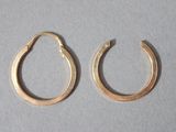 two pairs of gold hoop earrings on a white surface