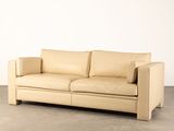 a tan leather couch in a room with a white wall