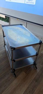 une table en métal avec un plateau en verre posée sur un parquet en bois massif