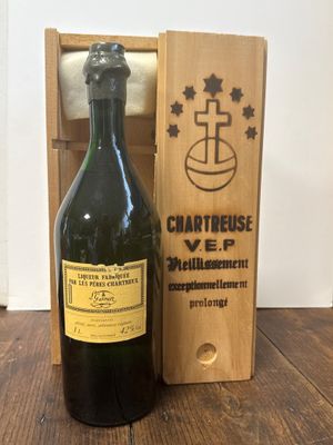 une vieille bouteille de vin dans une caisse en bois, à côté d'une bouteille de vin