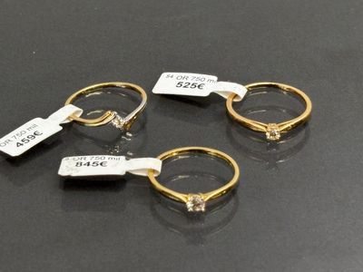 trois bagues en or munies d'étiquettes, posées sur une table