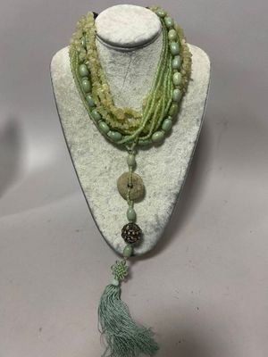 un gros plan d'un collier porté par un mannequin, orné d'un pompon