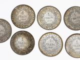 a group of six silver coins sitting on top of a white surface