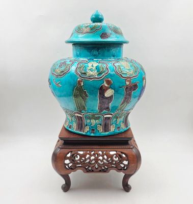 un vase bleu muni d'un couvercle, posé sur un socle