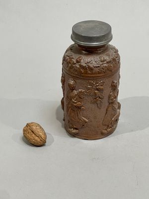 a small jar with a lid and a nut on the ground