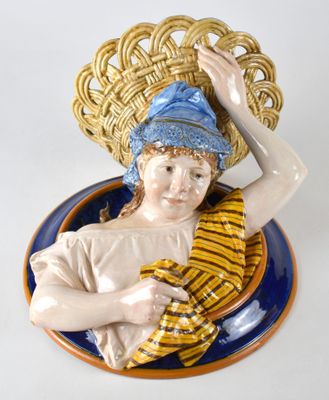 une figurine représentant un garçon avec un panier sur la tête