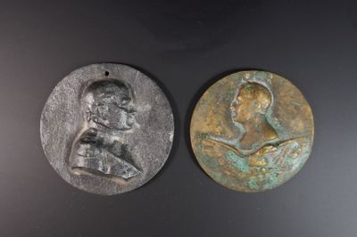 deux médaillons en bronze représentant un homme et une femme sur un fond noir