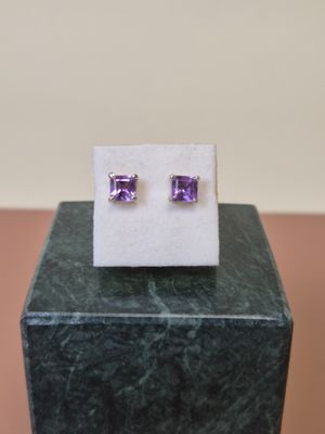 une paire de boucles d'oreilles en pierre violette posées sur un bloc de marbre