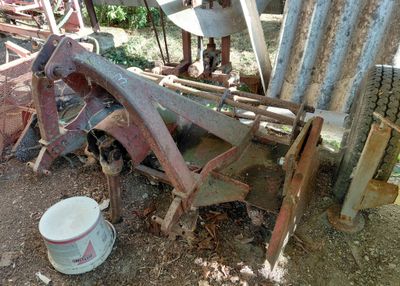 un tracteur rouillé avec un seau de peinture à côté