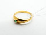 Gros plan sur une bague en or ornée d'une pierre verte
