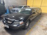 a black limousine parked in a parking lot next to other cars