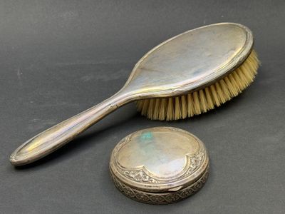 une brosse en argent et un miroir posés sur une table