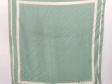a green and white square scarf hanging on a wall