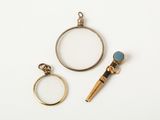 two rings, a magnifying glass and a ring with a blue stone