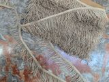 un sac en paille orné d'une frange, posé sur une table