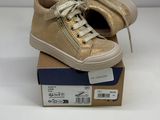 the gold sneakers are sitting on top of a cardboard box
