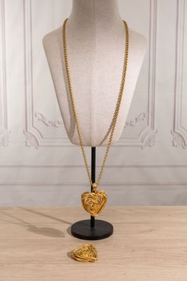 a gold necklace with a heart pendant on a mannequin stand