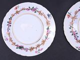two plates with floral designs are sitting on a black surface