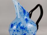 un pichet en verre bleu et noir muni d'une anse noire