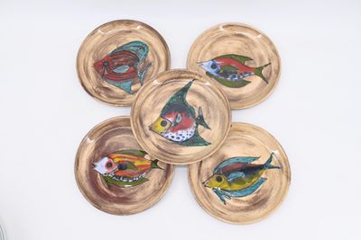 four plates with fish painted on them on a white surface