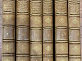 six vieux livres sont alignés sur une table en bois