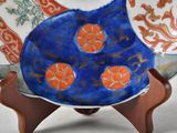 a blue plate with orange flowers on it on a wooden stand